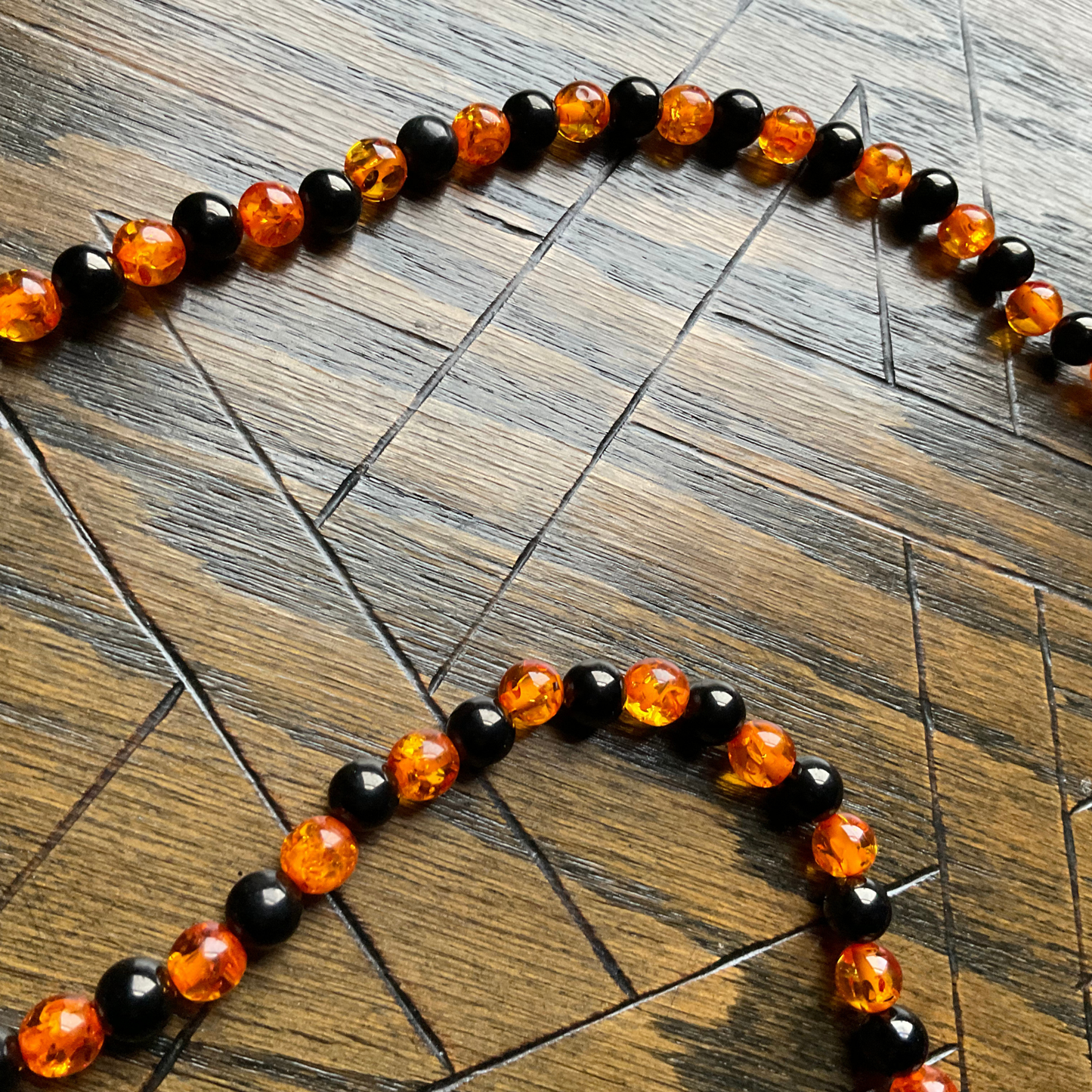 Necklace with large black and orange jet and amber beads on a wooden surface.