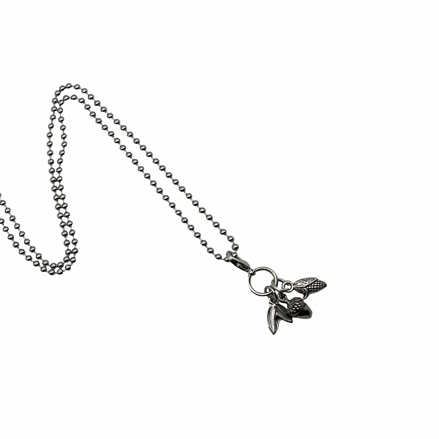 Necklace with a small pendant with three Autumn charms on a white background…an acorn, a leaf and an ear of harvest corn