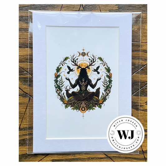 A art print featuring a black Cernunnos silhouette figure with deer antlers and a golden sun, surrounded by green foliage and birds, a wolf and a deer, in a white mat, presented in a clear protective sleeve on a rustic wood background. The Witch Joseph logo is visible in the right hand lower corner.
