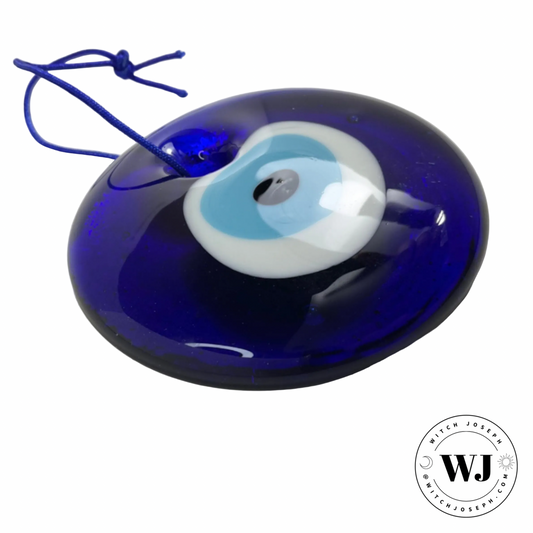 Blue glass evil eye glass ornament with a white and blue design displayed on a white background