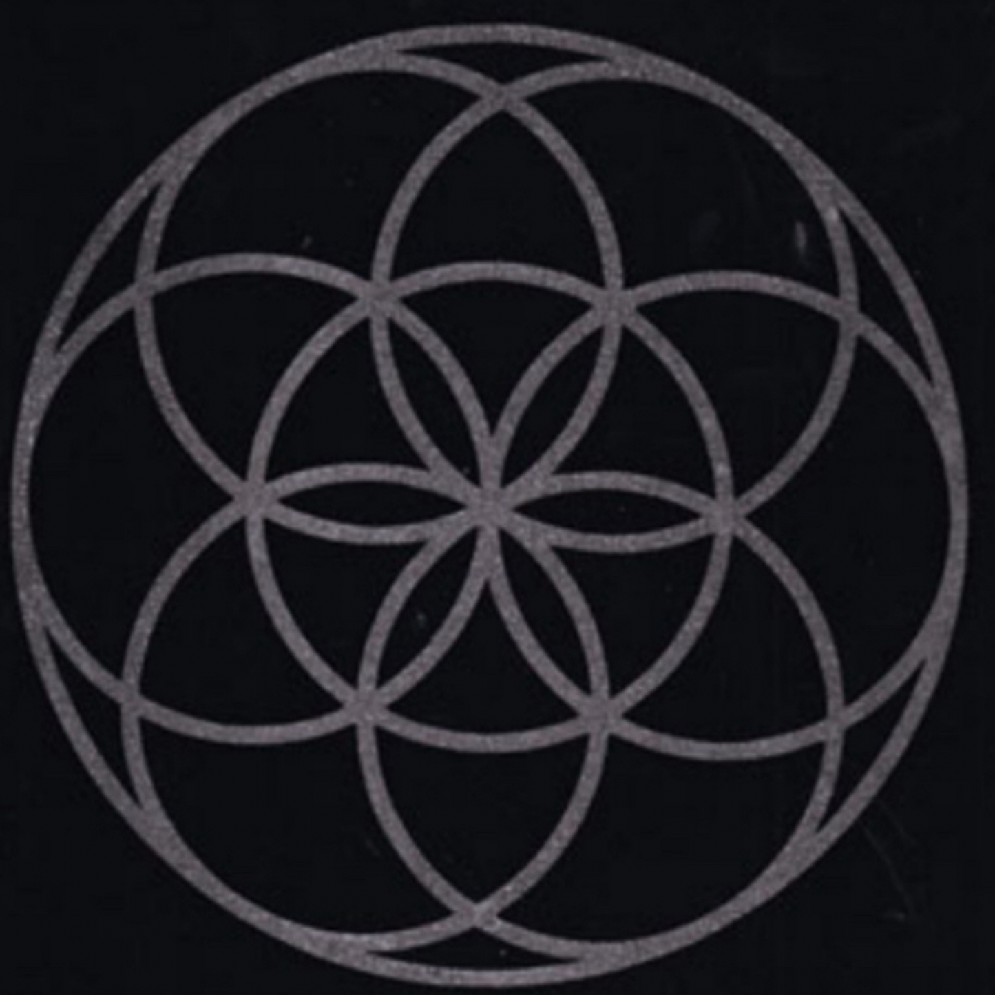 Geometric flower of life design of interlocking circles on a black background mat