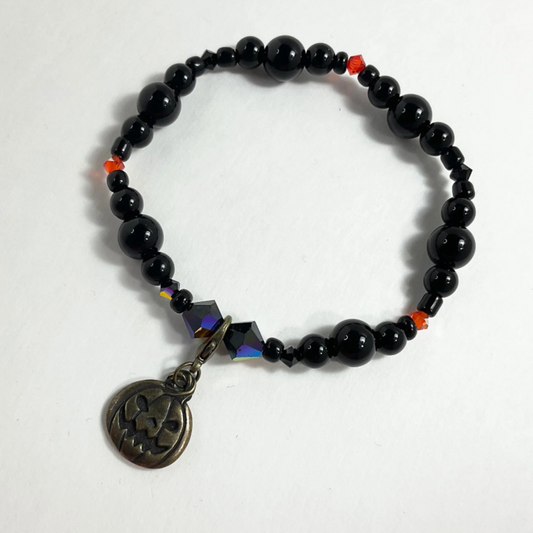 Black beaded bracelet with a jack o lantern pendant on a white background