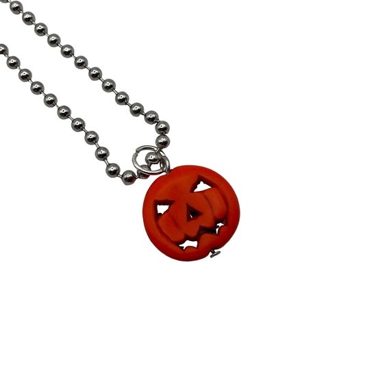 Necklace with a orange jack o lantern pumpkin charm on a silver tone ball chain on a white background