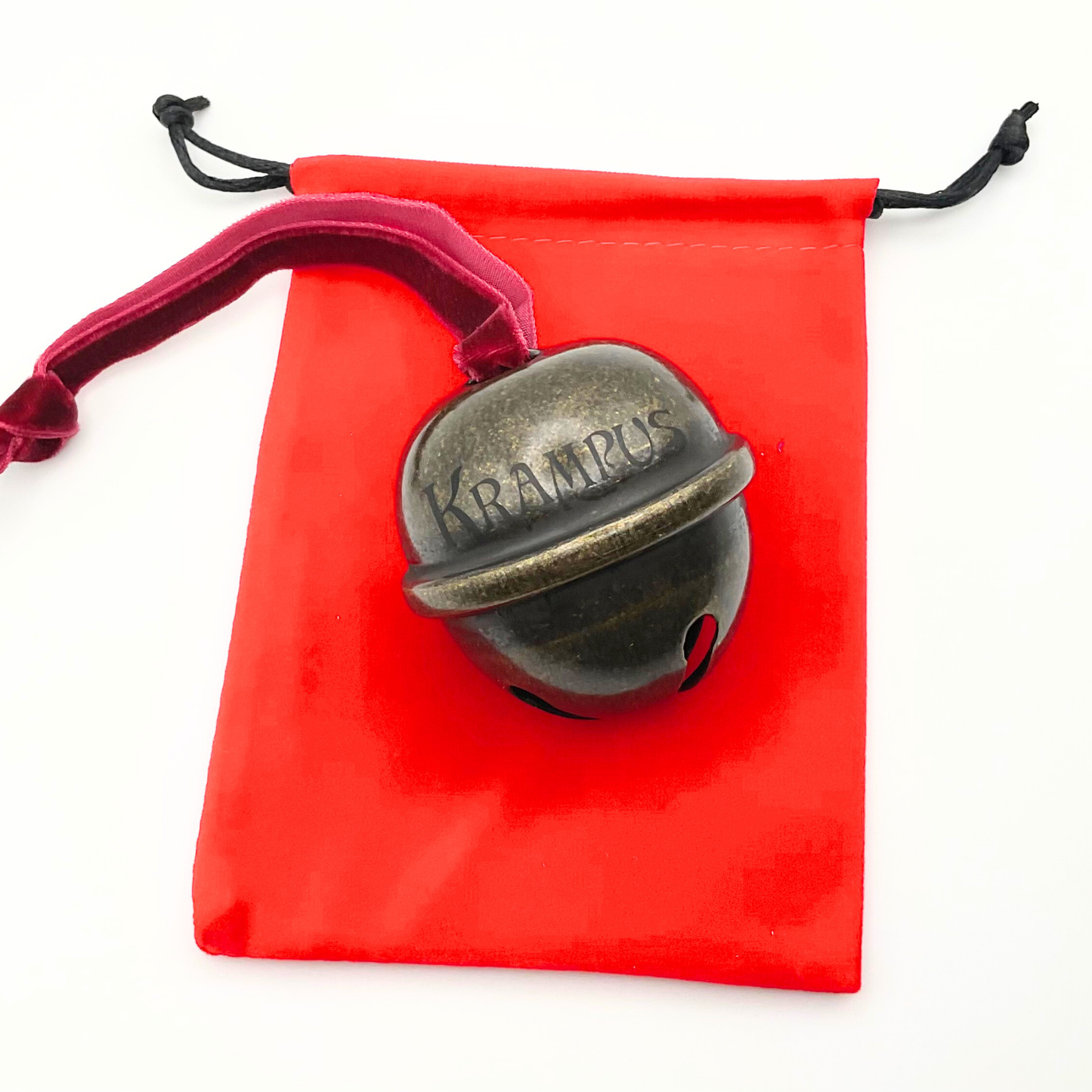 Bronze Krampus bell on a red drawstring bag with a white background