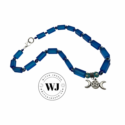 Blue beaded necklace with a silver triple Goddess pendant on a white background, featuring the brand 'Witch Joseph'.