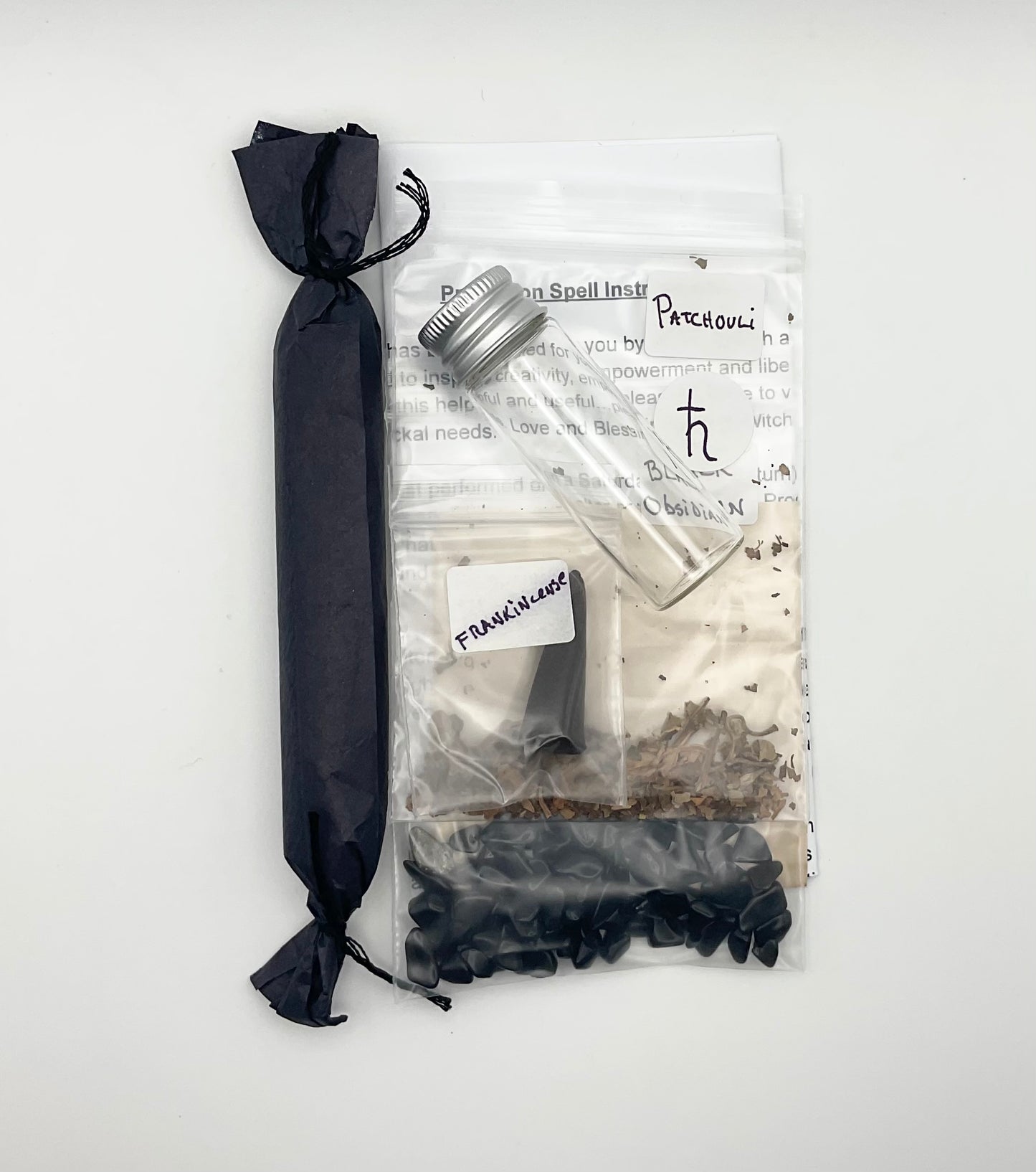 Packaged protection spell items including a black candle, herbs, crystals and instructions on a white background
