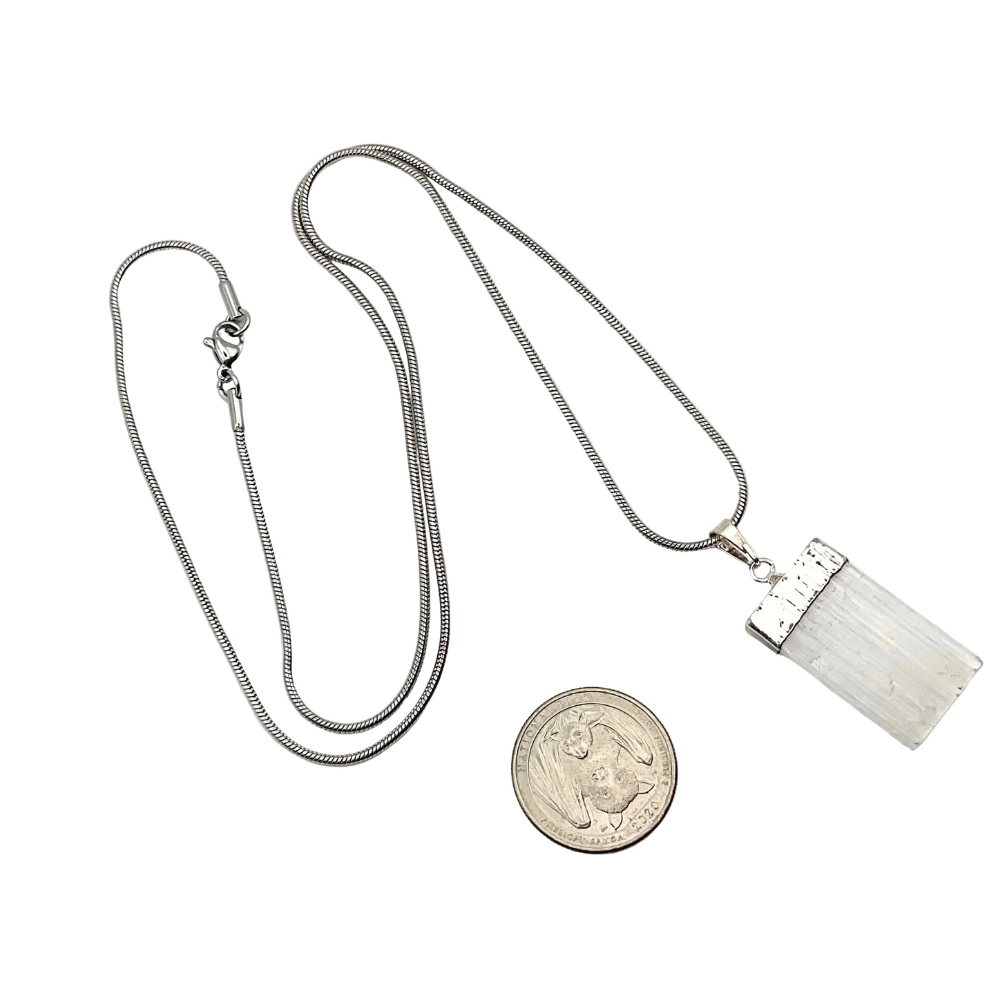 Silver necklace with a selenite pendant on a white background with white roses in a garden