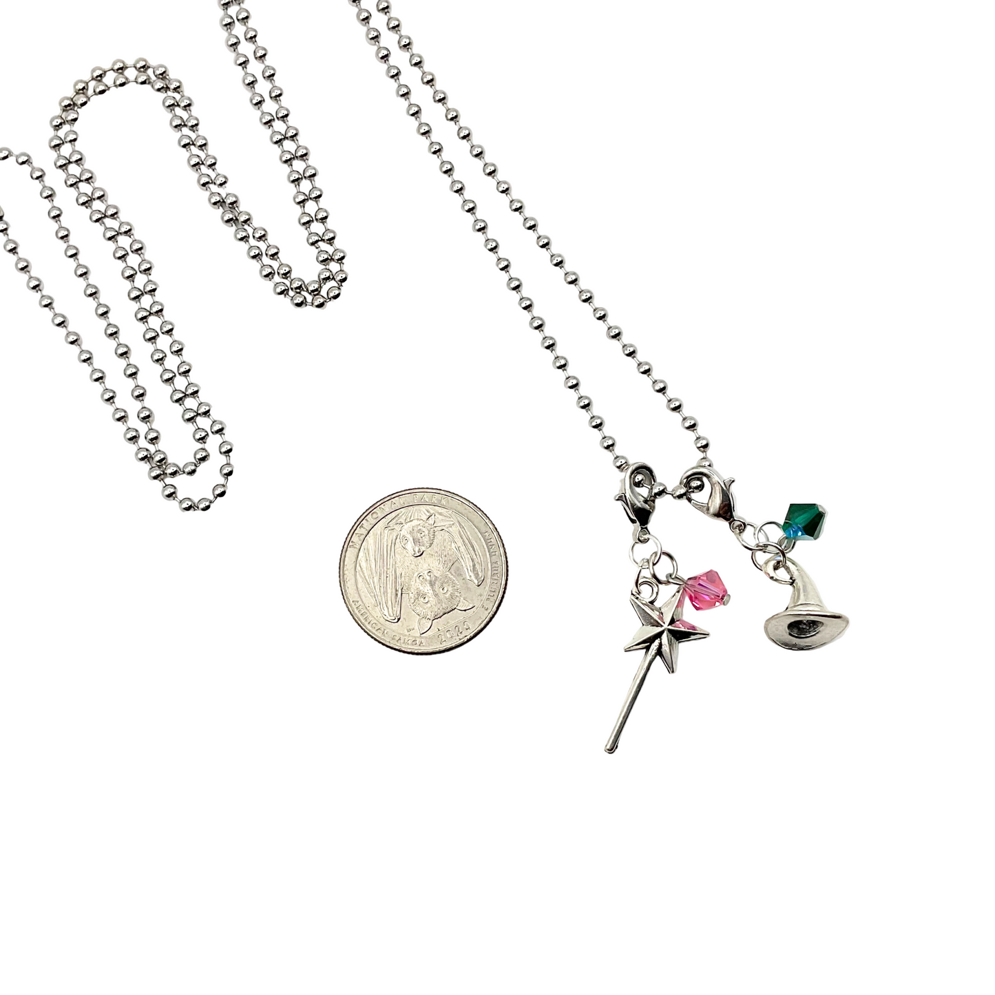 Necklace with various charms including witch hat with green bead and a magic wand with pink bead on a white background