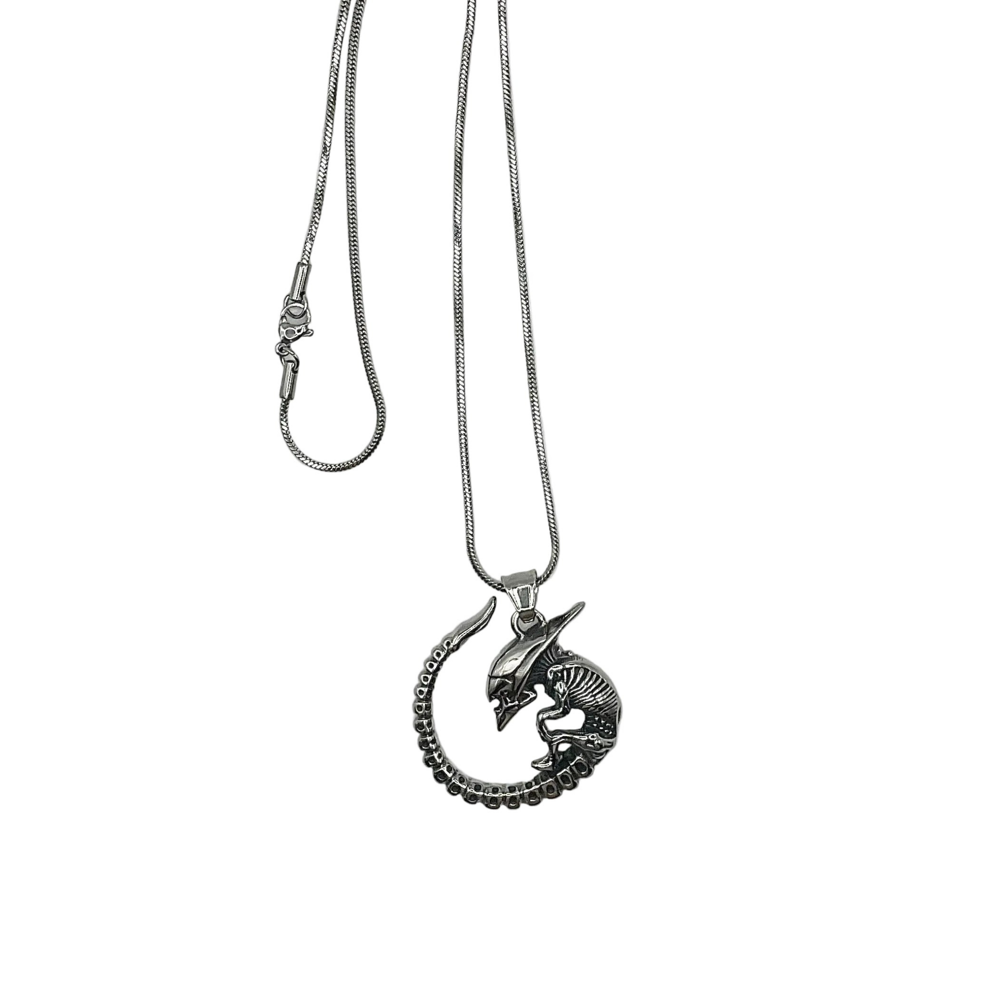Silver tone necklace with a unique alien baby monster pendant on a white background