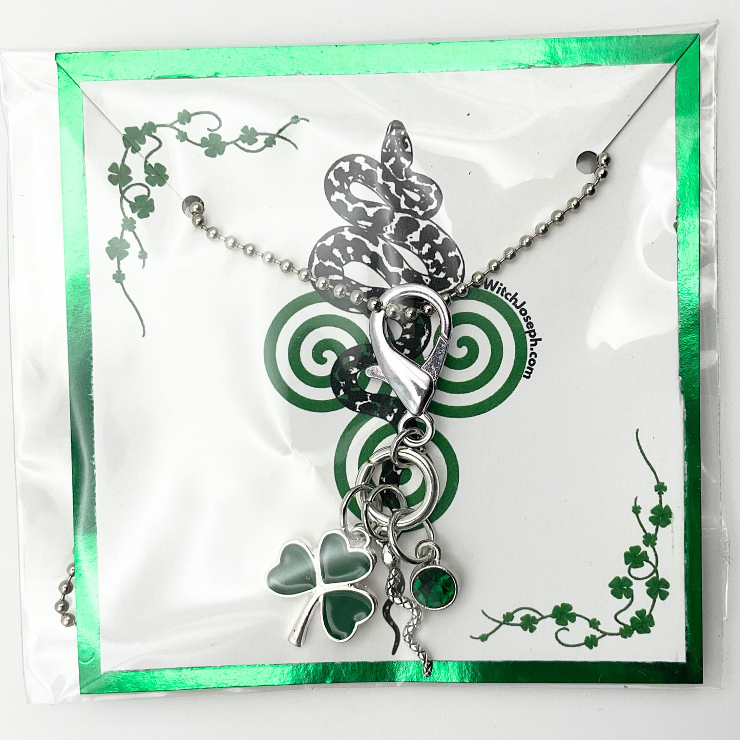 Silver All Snakes Day necklace with shamrock, snake and green crystal charms packaged on a decorative card with green Irish Pagan accents.