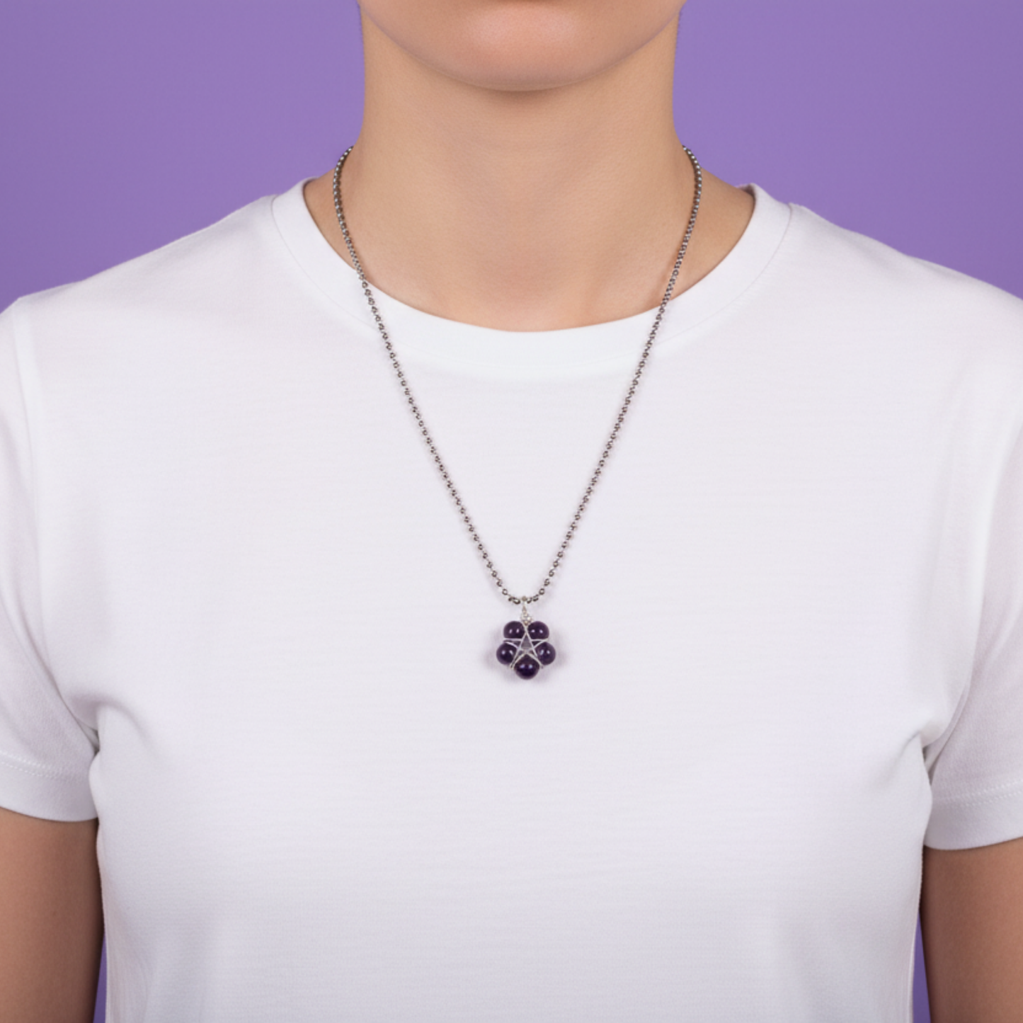 Person wearing a necklace with an amethyst purple bead pentagram pendant wearing a white shirt against a purple background