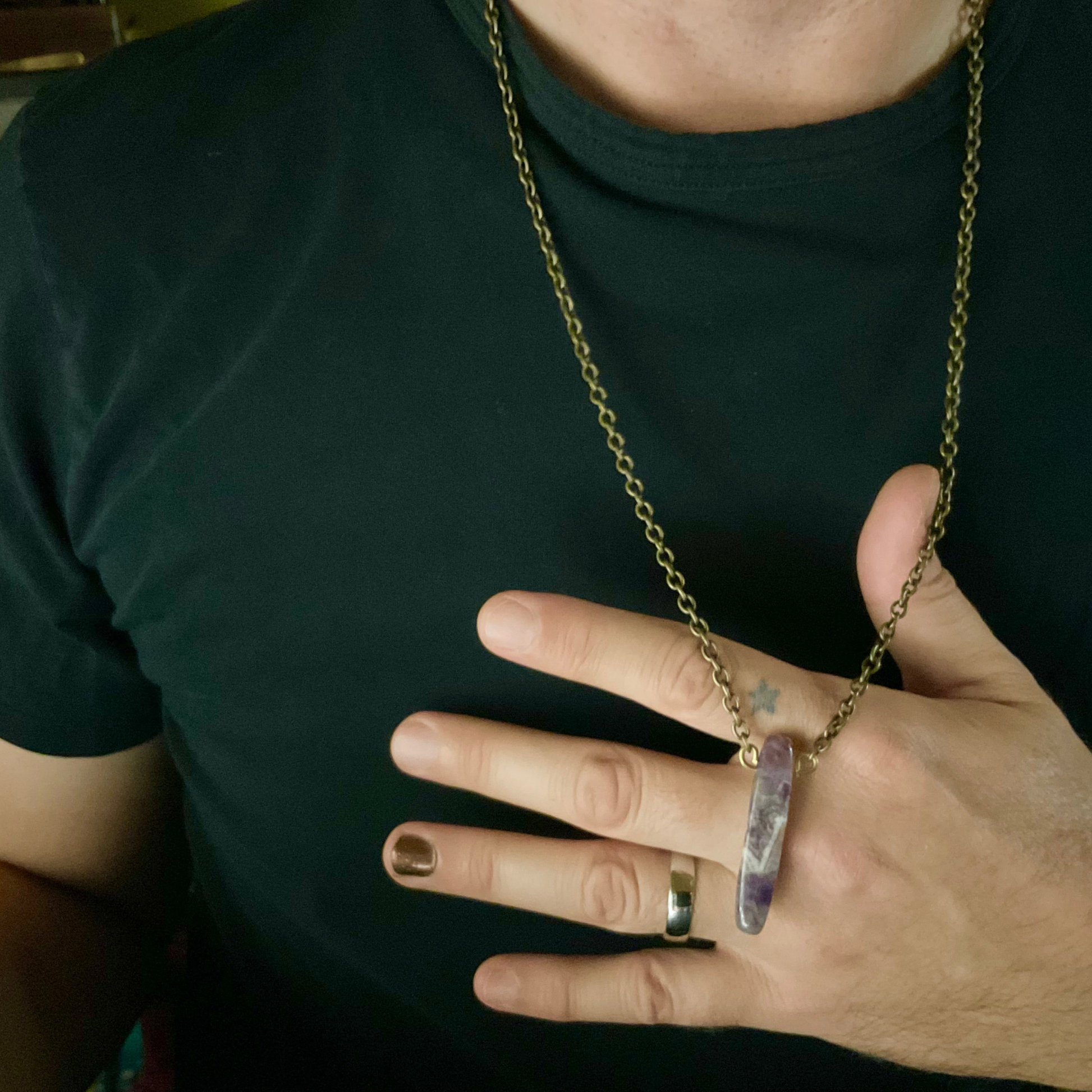 Person wearing a bronze tone chain necklace with parrot wing cut amethyst stone