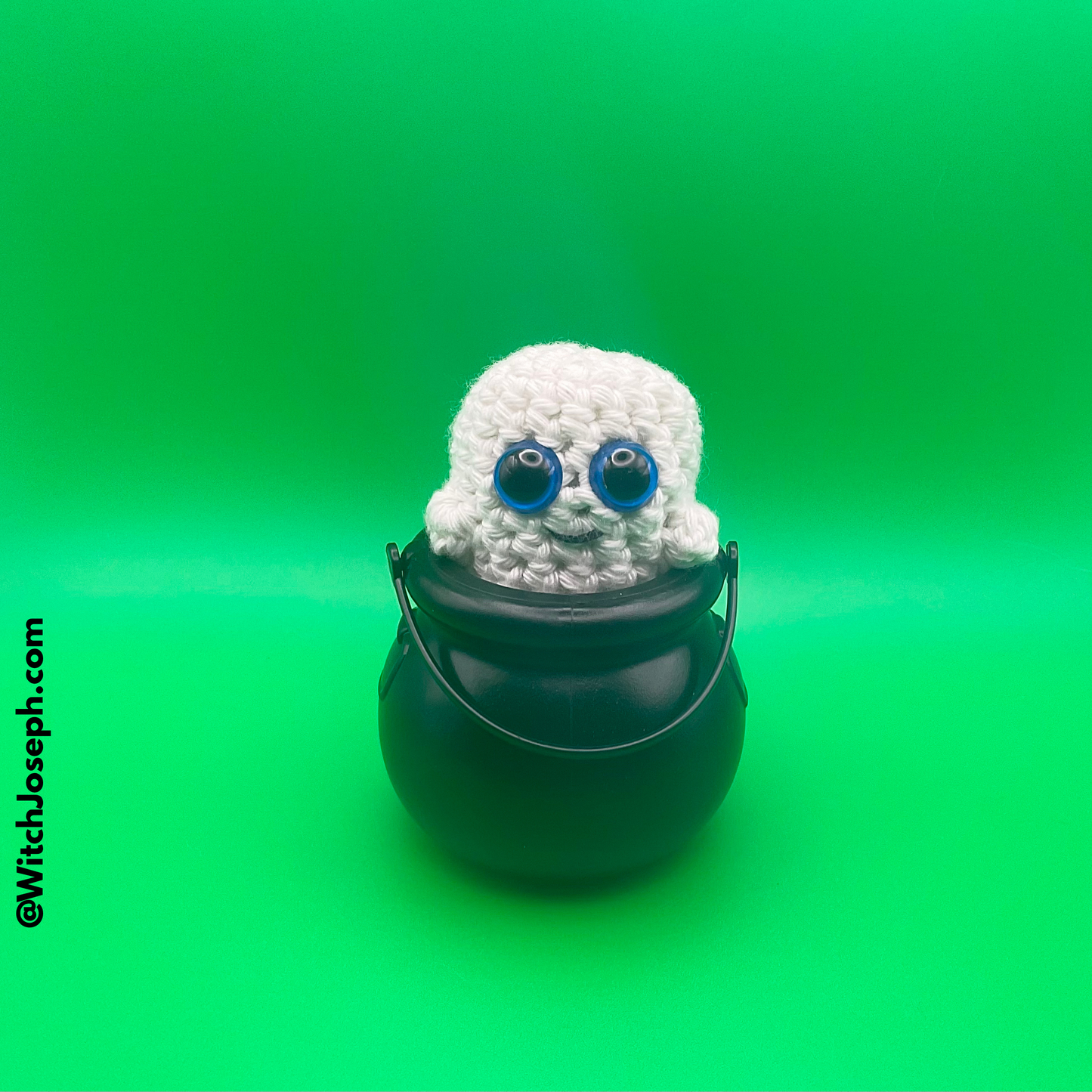 Crocheted ghost in a black pot on a green background with the Witch Joseph URL