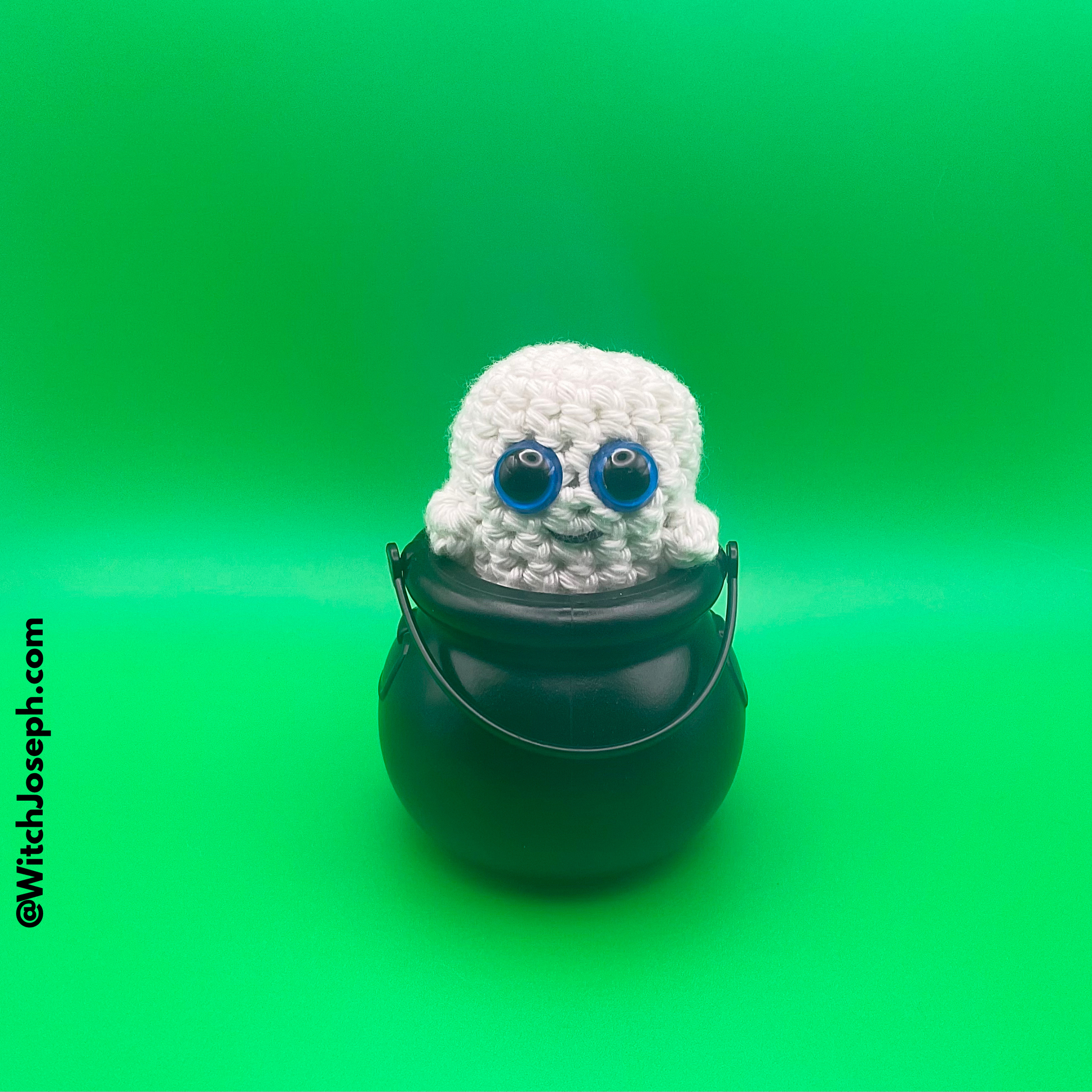 Crocheted ghost in a black pot on a green background with the Witch Joseph URL