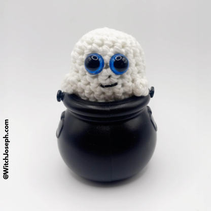 Small white Ghost creature with blue eyes inside a black pot on a white background with the Witch Joseph URL