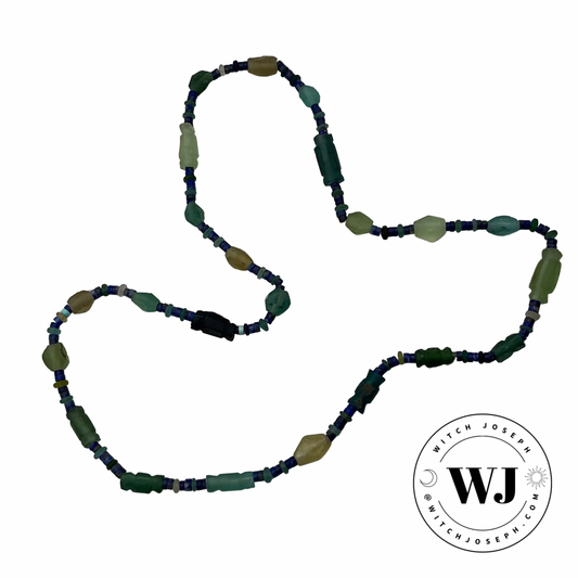Beaded necklace with ancient Roman glass and lapis lazuli green and blue beads necklace displayed on a white background, featuring the logo 'Witch Joseph'.