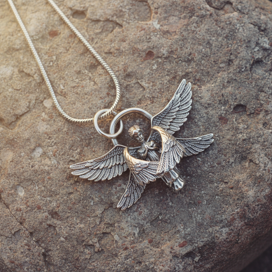 Silver tone angel pendant necklace displayed on a rustic stone surface