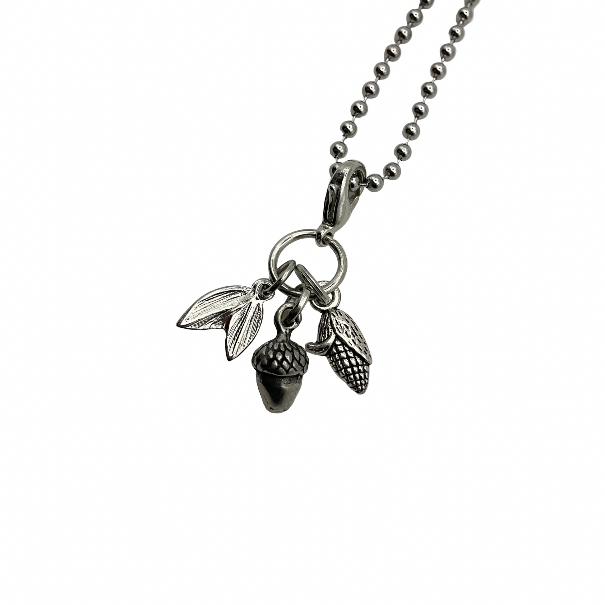 Silver tone necklace with acorn, corn and leaf charms on a white background