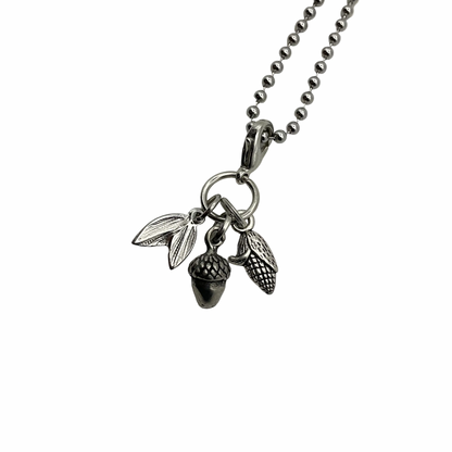 Silver tone necklace with acorn, corn and leaf charms on a white background