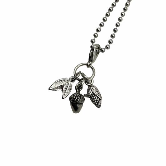 Silver tone necklace with acorn, corn and leaf charms on a white background