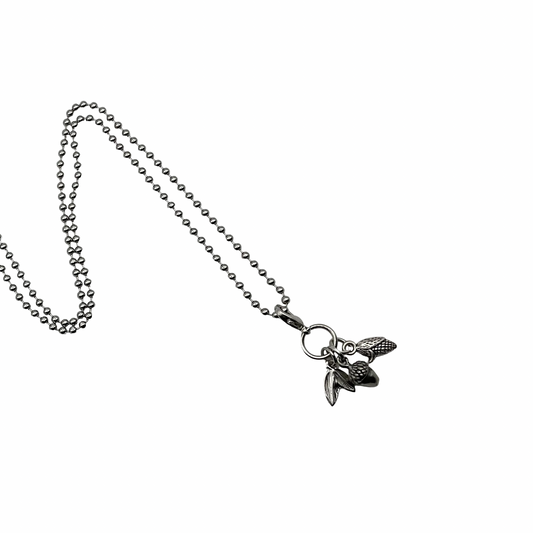 Necklace with a small pendant with three Autumn charms on a white background…an acorn, a leaf and an ear of harvest corn