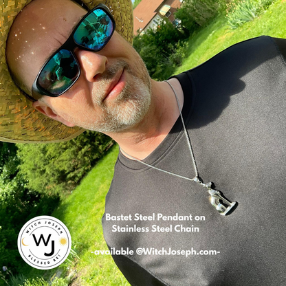 Man wearing sunglasses and a straw hat modeling our Bast cat pendant necklace…standing outdoors in the Garden with the Witch Joseph logo