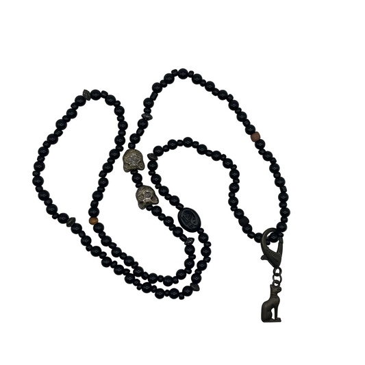 Black beaded necklace with decorative cat bead elements and a bronze tone Bastet cat pendant displayed on a white background