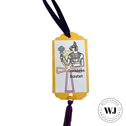 Decorative tag with illustration of Goddess Bastet and purple tassel on white background