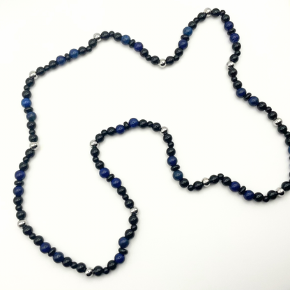 Blue Lapis Lazuli beaded necklace with black and steel bead accents against a white background.