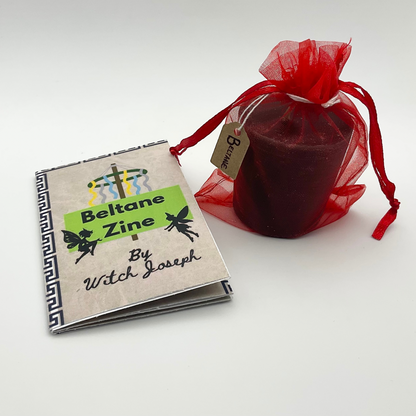 Contents of the Beltane Candle Lighting Kit…Beltane Zine by Witch Joseph with a red Beltane candle in a sheer bag on a white background