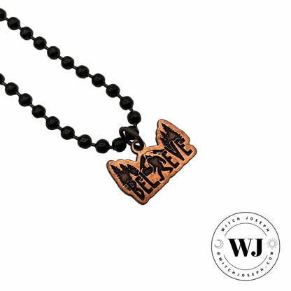 the Bigfoot copper charm necklace…pendant shows an etching of Bigfoot against a backdrop of trees and mountain…displayed against a white background with the Witch Joseph logo