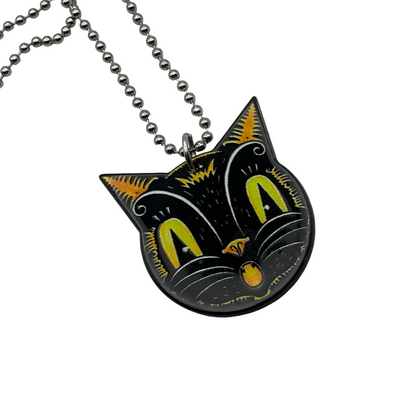 Shows the Vintage style Black and yellow cat-shaped surprised face on the reverse side of the  pendant on a ball chain against a white background