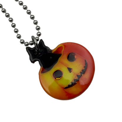 Vintage style Halloween-themed necklace with a cat in a jack-o'-lantern pendant on a ball chain against a white background