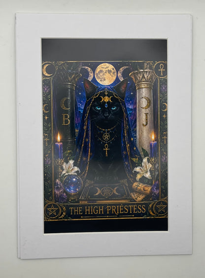 A matted art print featuring a dark, mystical tarot-style illustration of a black cat dressed as a high priestess under a full moon, with ornate gold details, candles, flowers, and the text 'THE HIGH PRIESTESS' at the bottom. The print is mounted with a wide white border against a light gray wall.