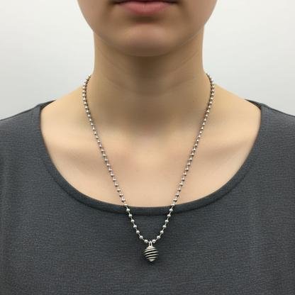 Person wearing a necklace with a black obsidian chip in a cage pendant against a neutral background