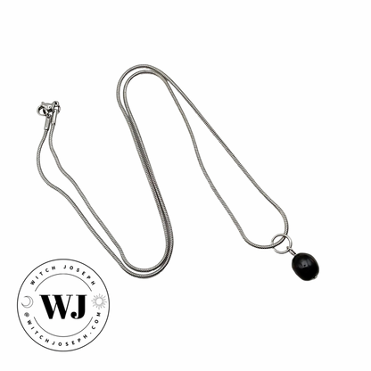 Silver tone necklace with a black pearl drop pendant on a white background, featuring the WJ logo.