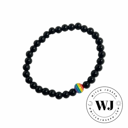 Black beaded stretch bracelet with a rainbow focal bead displayed on a white background, featuring the WJ logo