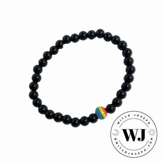 Black beaded stretch bracelet with a rainbow focal bead displayed on a white background, featuring the WJ logo