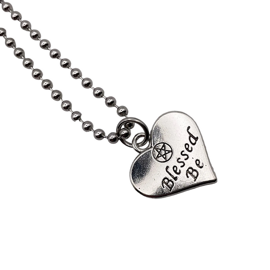 Silver tone necklace with a heart-shaped pendant that says 'Blessed Be' on a white background.