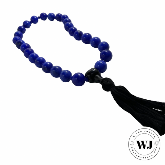 Blue beaded Mala for chanting and praying with a black tassel on a white background, branded with 'WJ'.