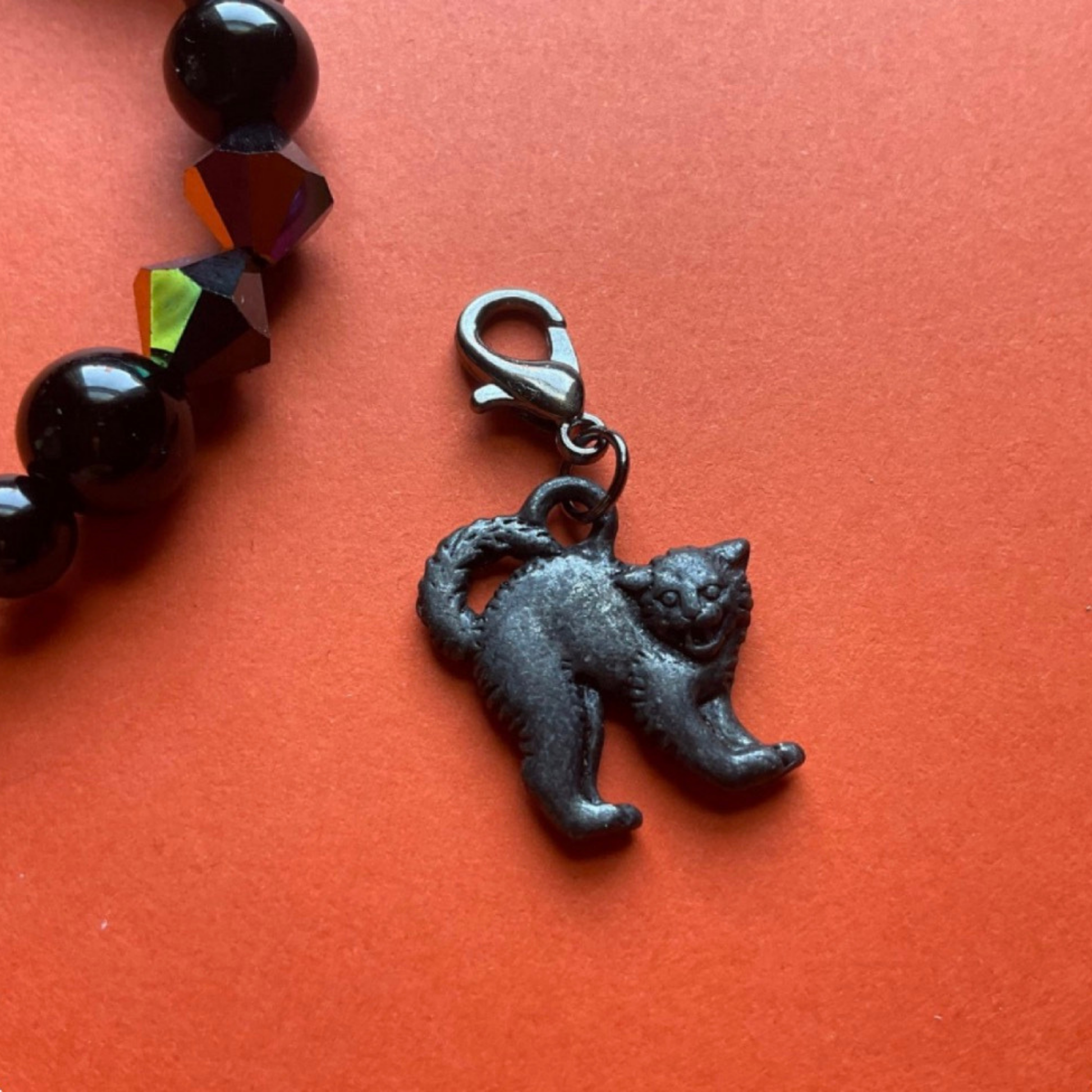 Cat-shaped charm and bracelet displayed on an orange background