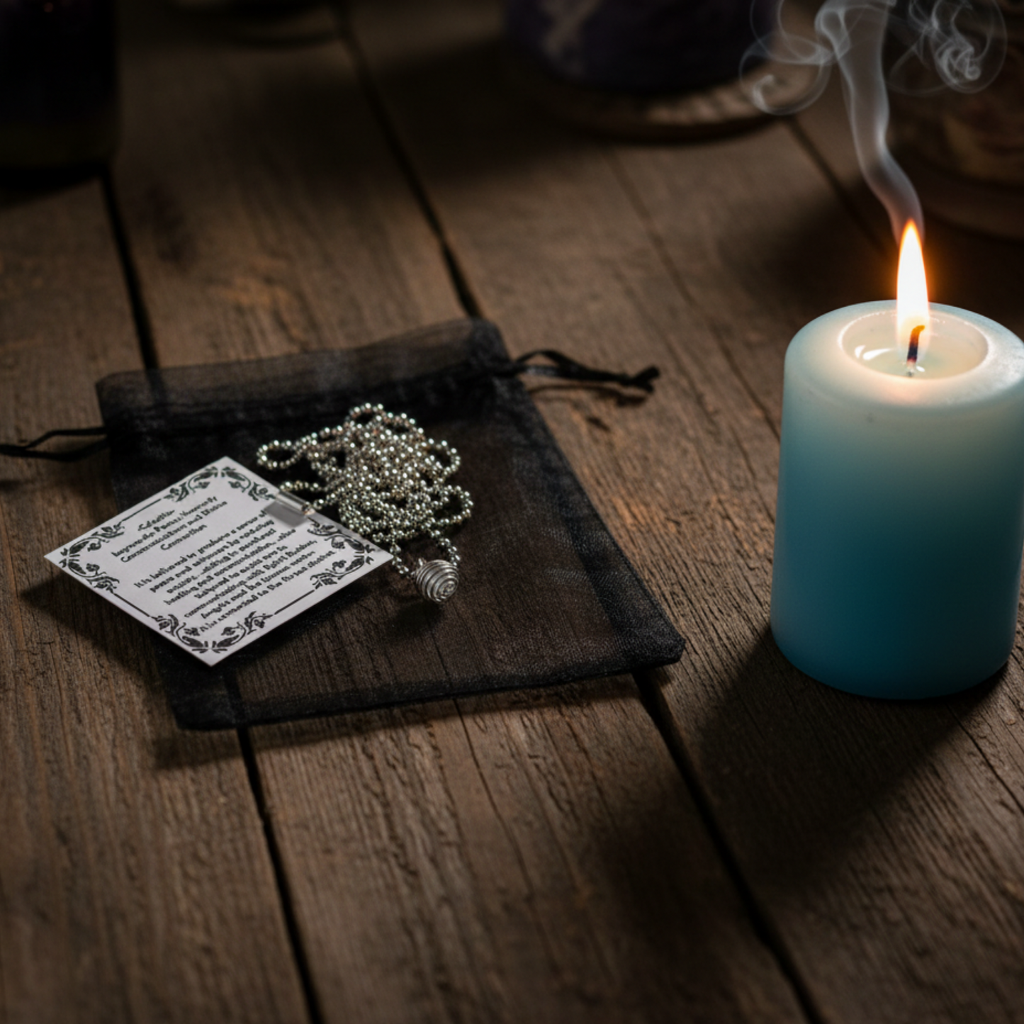 Silver tone celestite chip cage necklace on a ball chain laying on a wooden surface