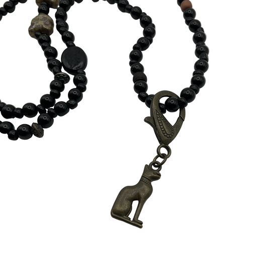 Black beaded necklace with cat beads and with a bronze cat pendant on a white background