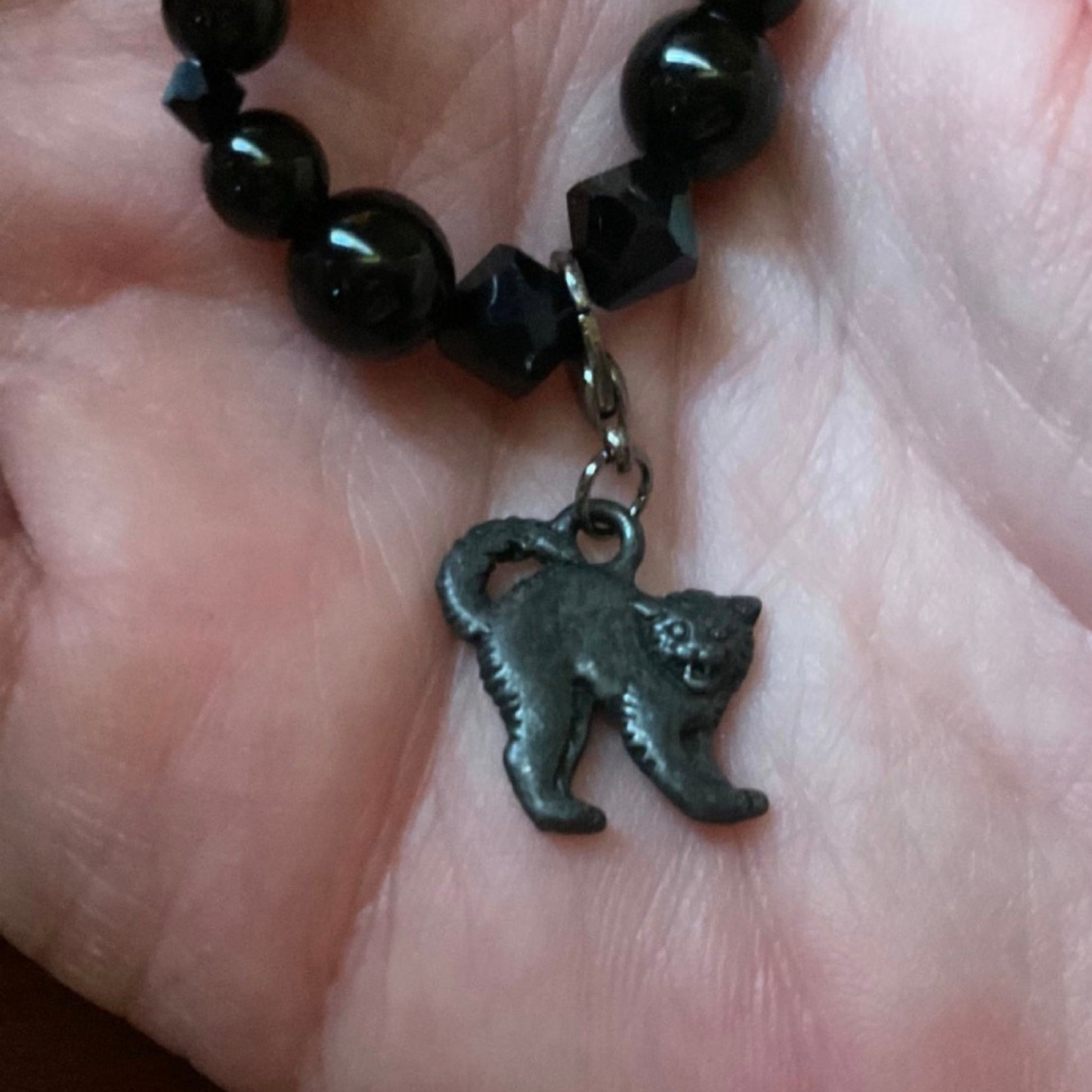 Black beaded bracelet with a cat charm on a hand