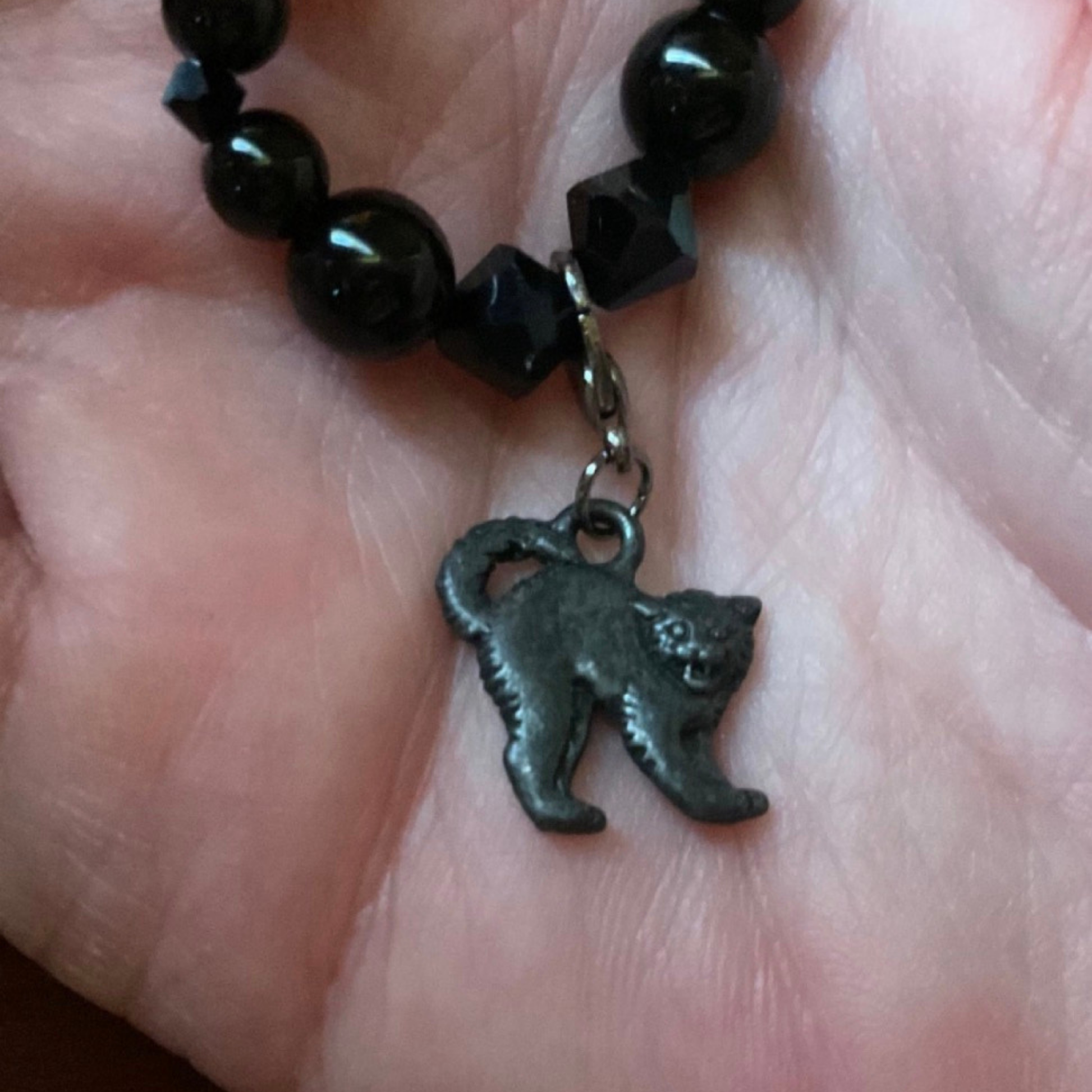 Black beaded bracelet with a cat charm on a hand