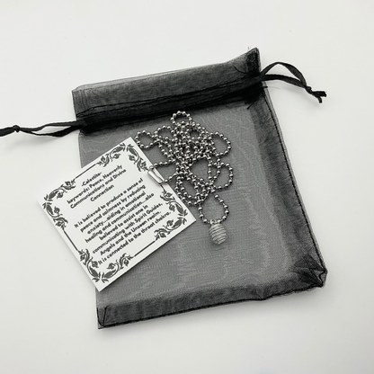 Necklace with silver tone celestite chip cage pendant and metaphysical properties stickerin a black organza drawstring bag on a light background