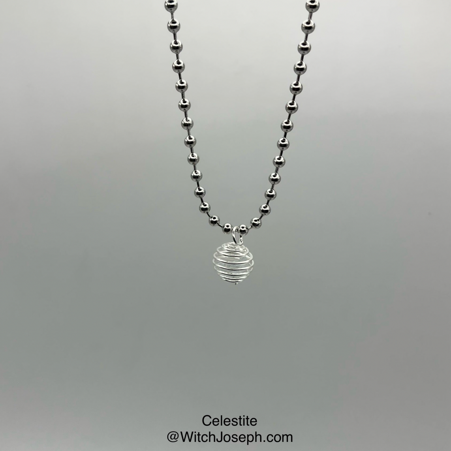 Necklace with celestite chip cage pendant on a gray background