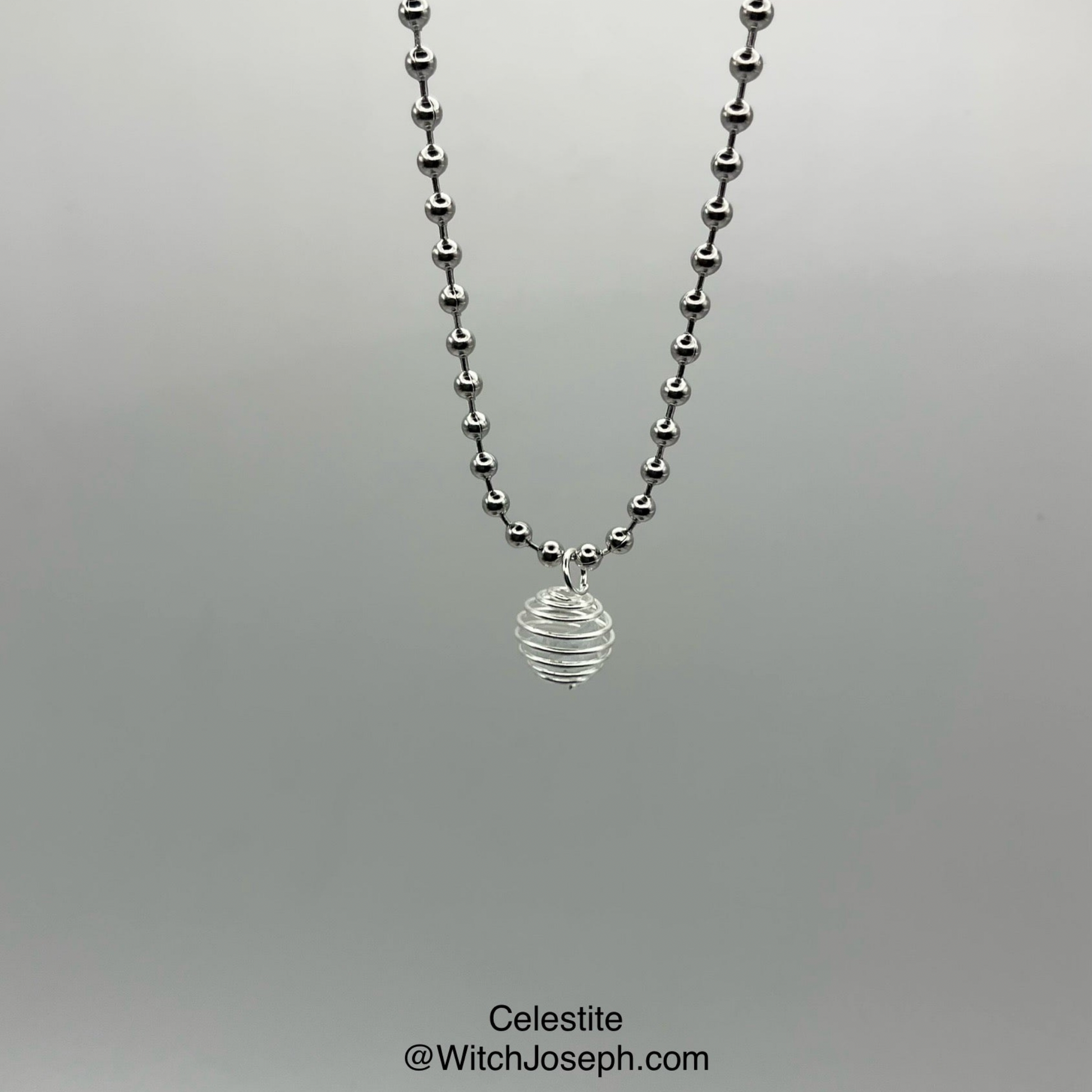 Necklace with celestite chip cage pendant on a gray background