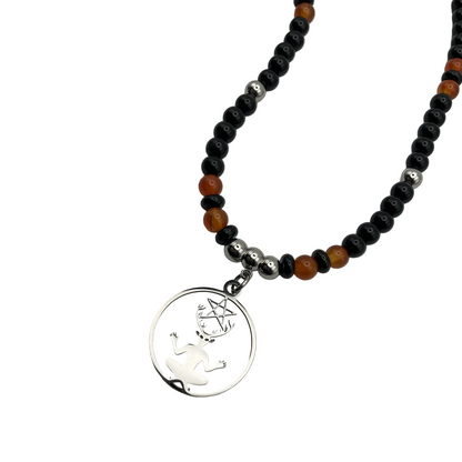 Necklace with black, orange, and silver beads and a silver Cernunnos pendant on a white background