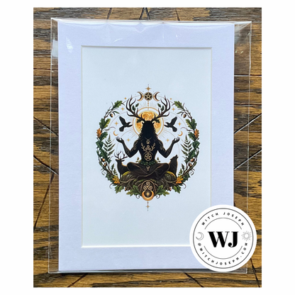A art print featuring a black Cernunnos silhouette figure with deer antlers and a golden sun, surrounded by green foliage and birds, a wolf and a deer, in a white mat, presented in a clear protective sleeve on a rustic wood background.  The Witch Joseph logo is visible in the right hand lower corner.